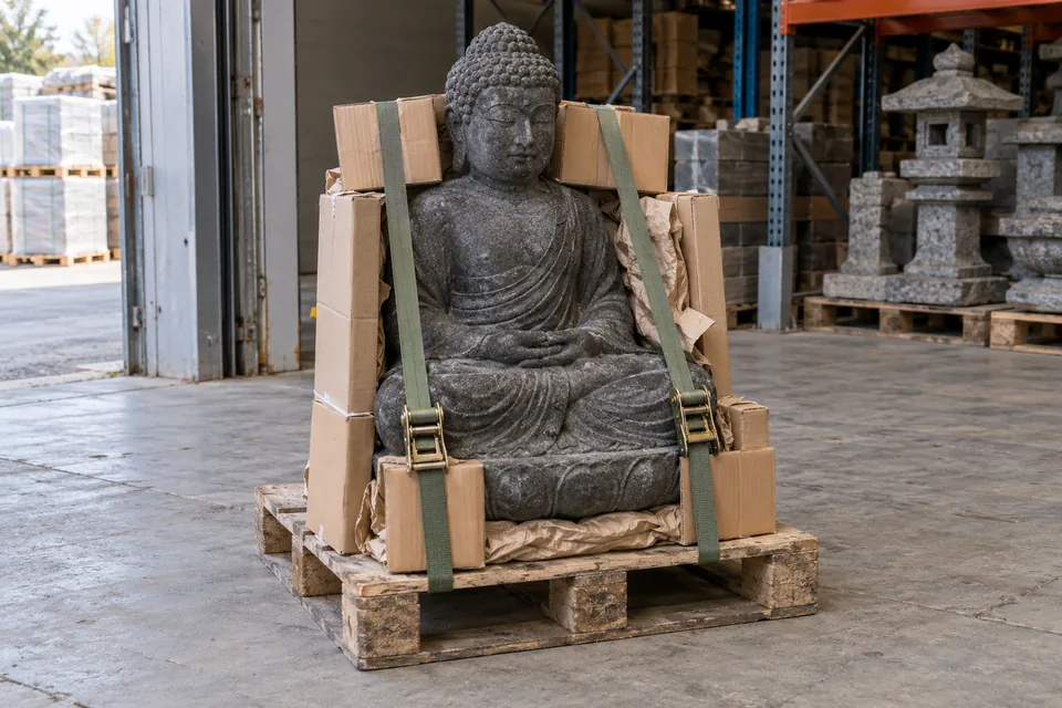 Schwere Buddha-Figur mit Kantenschutz und Gurten auf einer Transportpalette