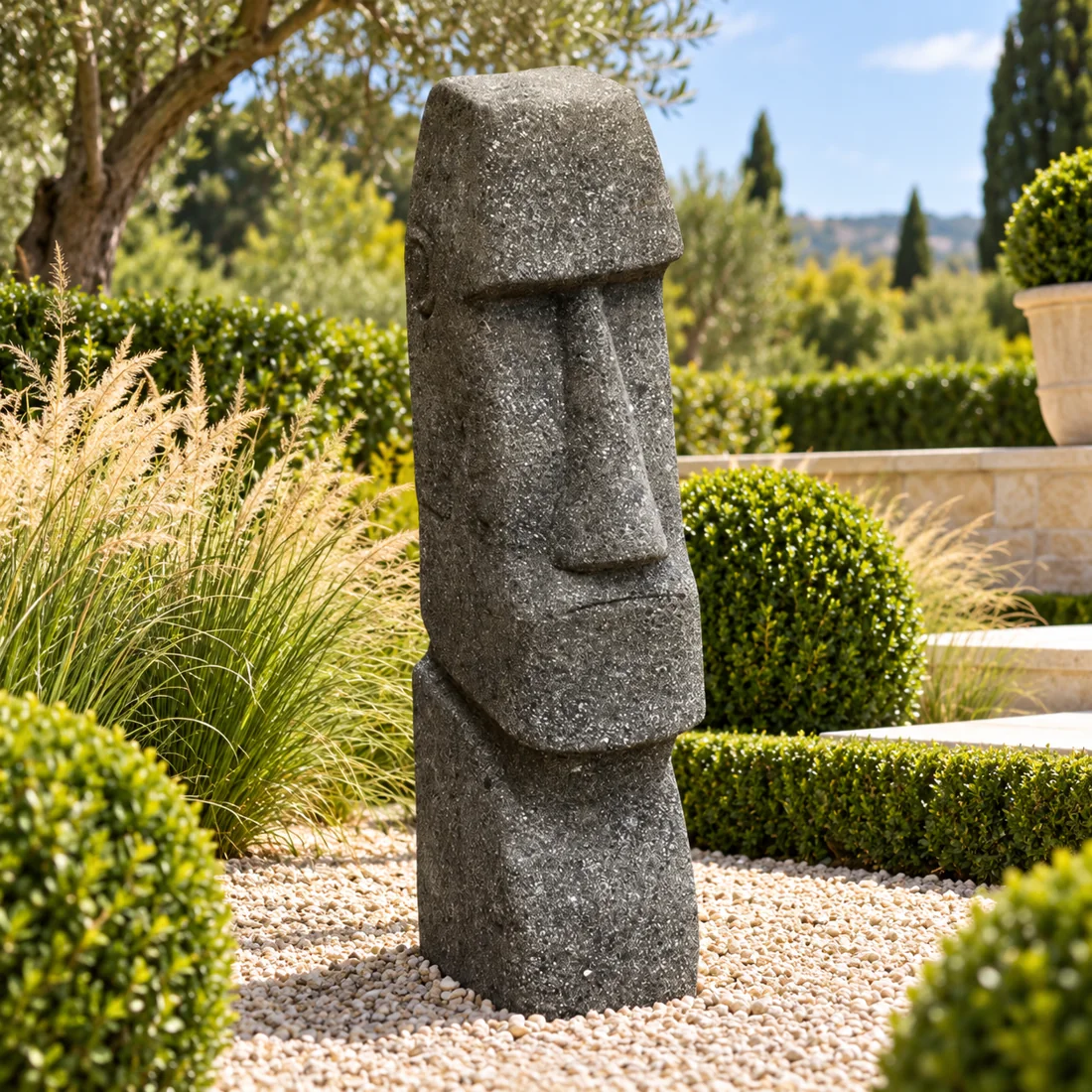 Moai-Gartenfigur vor mediterraner Bepflanzung